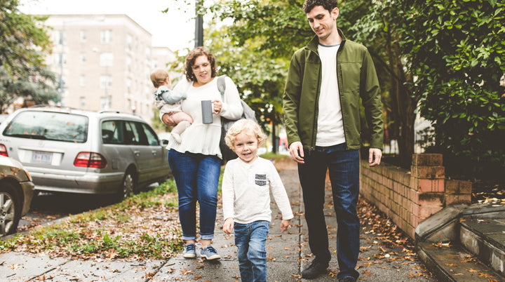 image of stressed out mom holding her head in her hand, with 2 children in the background