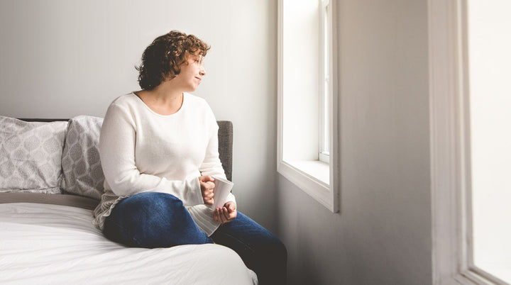 Mom sitting alone on edge of bed