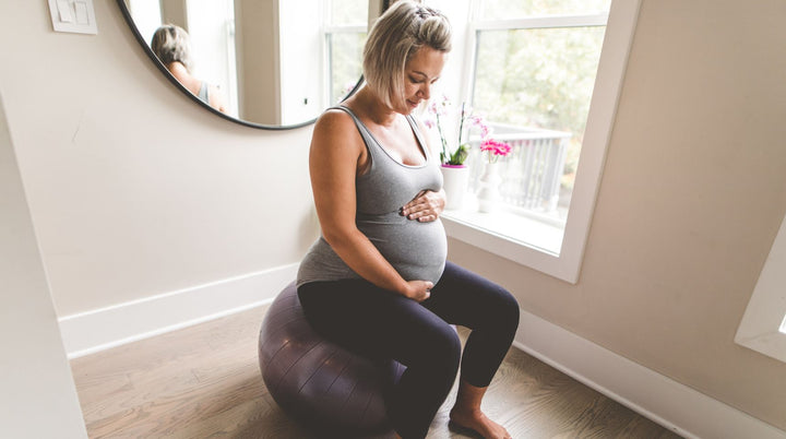 Pregnant mom sitting on edge of bed