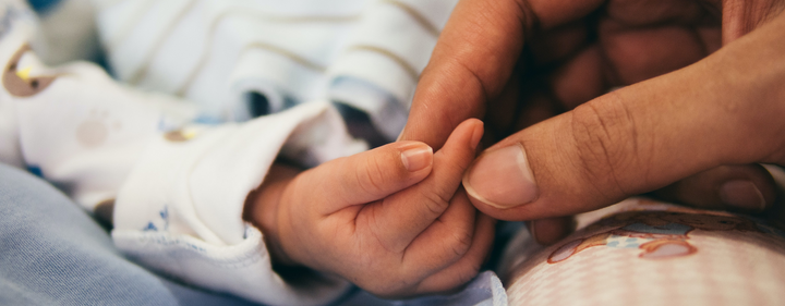 Mom hand touching baby's hand